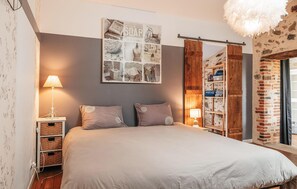 A bedroom with a bed, two bedside lamps, a wall-mounted picture, a wooden wardrobe, and a brick wall. - Gorgeous home in Sevremont with WiFi (Sevremont)