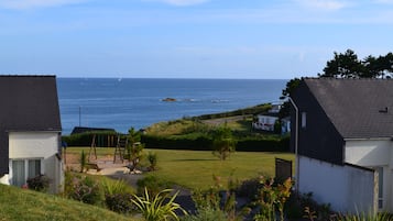 A coastal residential area with houses, a grassy lawn, and a view of the sea.
