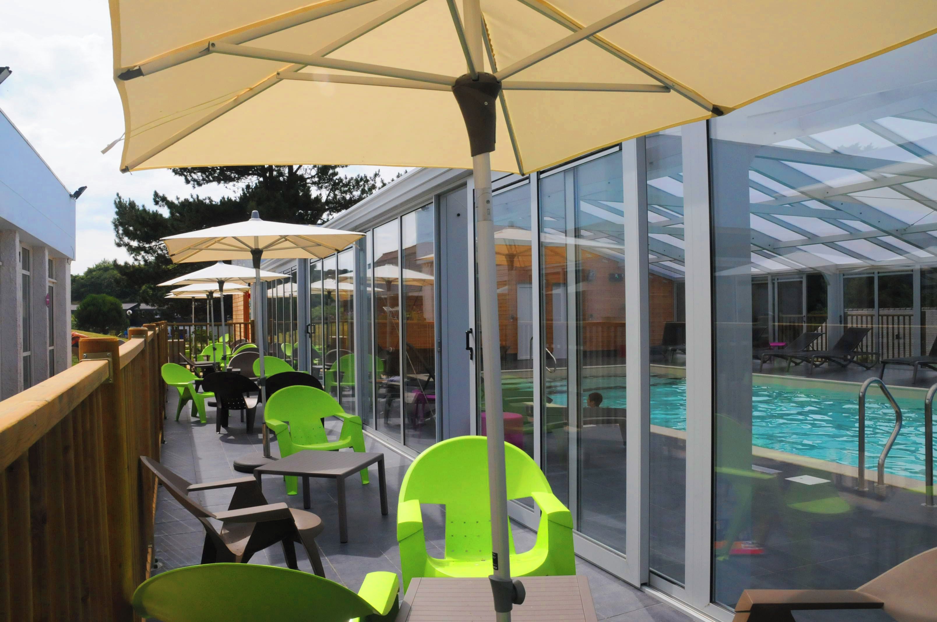 A poolside area with glass-enclosed seating and umbrellas.
