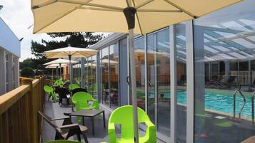 A poolside area with glass-enclosed seating and umbrellas.