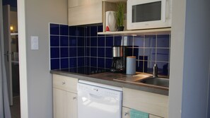A compact kitchen with a dishwasher, a coffee maker, and a microwave on the countertop. - Vvf Villages Saint-cast-le-guildo (Saint-Cast-le-Guildo)