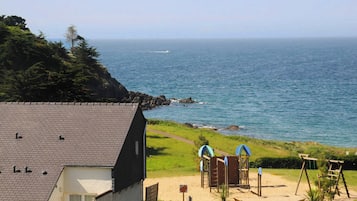 A coastal property with a view of the sea, a sandy beach, and a playground.