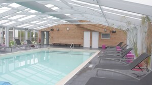 A swimming pool with lounge chairs, a wooden wall, and a skylight ceiling. - Vvf Villages Saint-cast-le-guildo (Saint-Cast-le-Guildo)