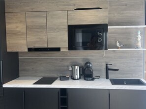 Eine moderne Küche mit Einbau-Mikrowelle, Kaffeemaschine und Spüle.