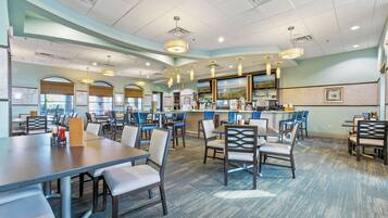 A spacious restaurant with high tables and chairs, a bar area, and a view through the windows.