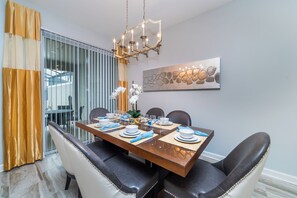Uma área de refeições com divisória de vidro, um candelabro e uma pintura abstrata moderna.