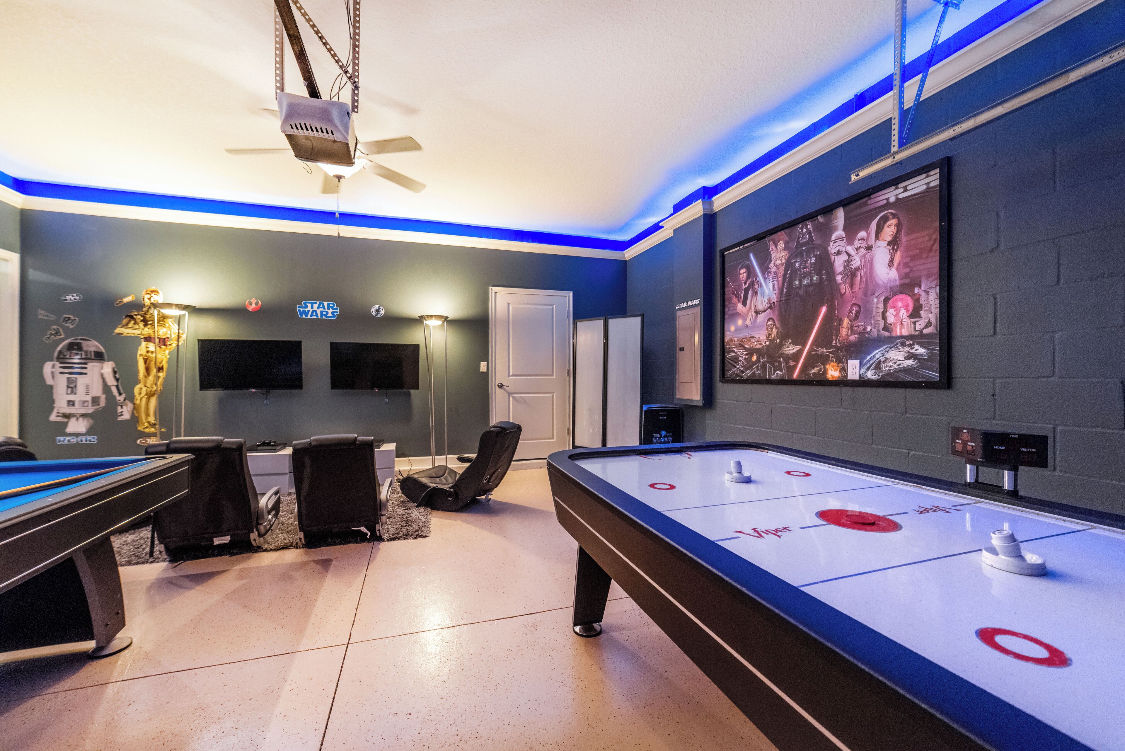 A room with a pool table, shuffleboard table, and Star Wars-themed decor.
