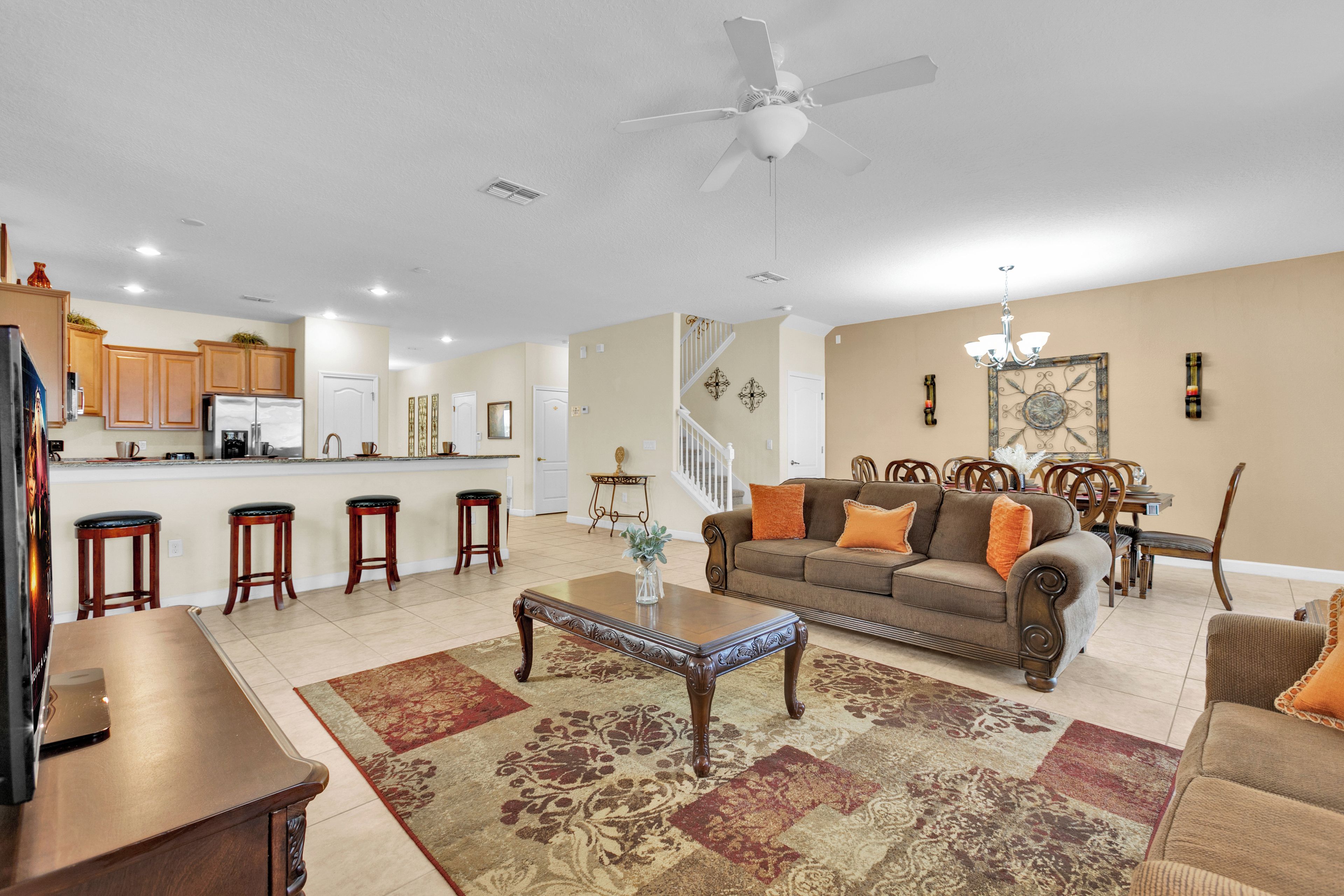 A spacious living room with a sofa, coffee table, and a kitchen area in the background.