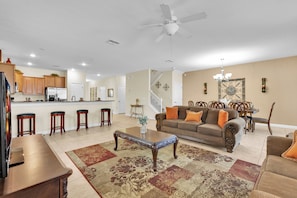 A spacious living room with a sofa, coffee table, and a kitchen area in the background. - Championsgate Resort Homes and Townhomes (Davenport)