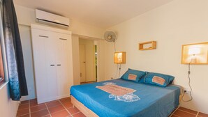 Une chambre avec un lit, un appareil de climatisation, un ventilateur et une armoire.