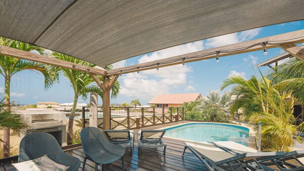 Un espace extérieur abrité comprenant une piscine, des chaises longues et une table.
