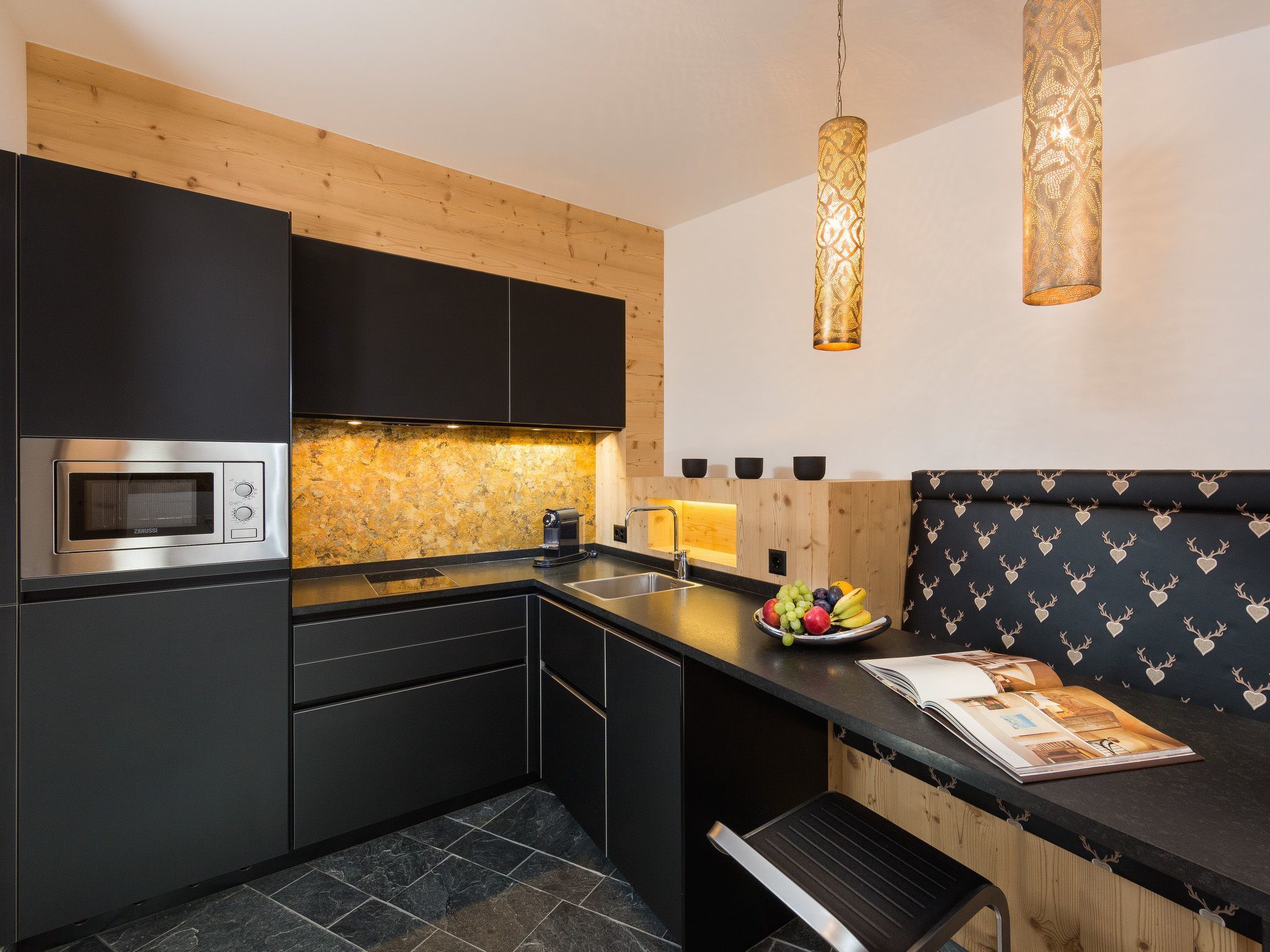 A modern kitchen with a built-in microwave, a sink, and a wooden backsplash.