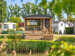 Eine Holzhütte mit Balkon, umgeben von Grünpflanzen und einem Teich.