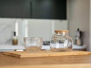 Ein klares Glasgefäß mit Holzdeckel und eine klare Glas-Schale auf einer Holztischplatte.