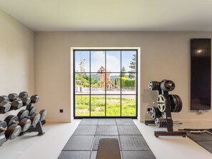 Ein Fitnessstudio mit großem Fenster, Gewichtsständern und Blick auf ein Gebäude.