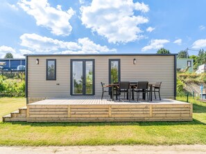 Ein modernes, eingeschossiges Gebäude mit einer Terrasse und Sitzgelegenheiten im Freien.