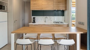 Una cocina moderna con encimera de madera, sillas blancas y estufa integrada.
