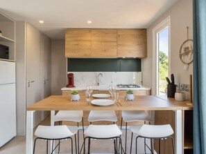 Una cocina moderna con armarios de madera, una isla central con sillas, una estufa a gas y un ventanal con vistas.