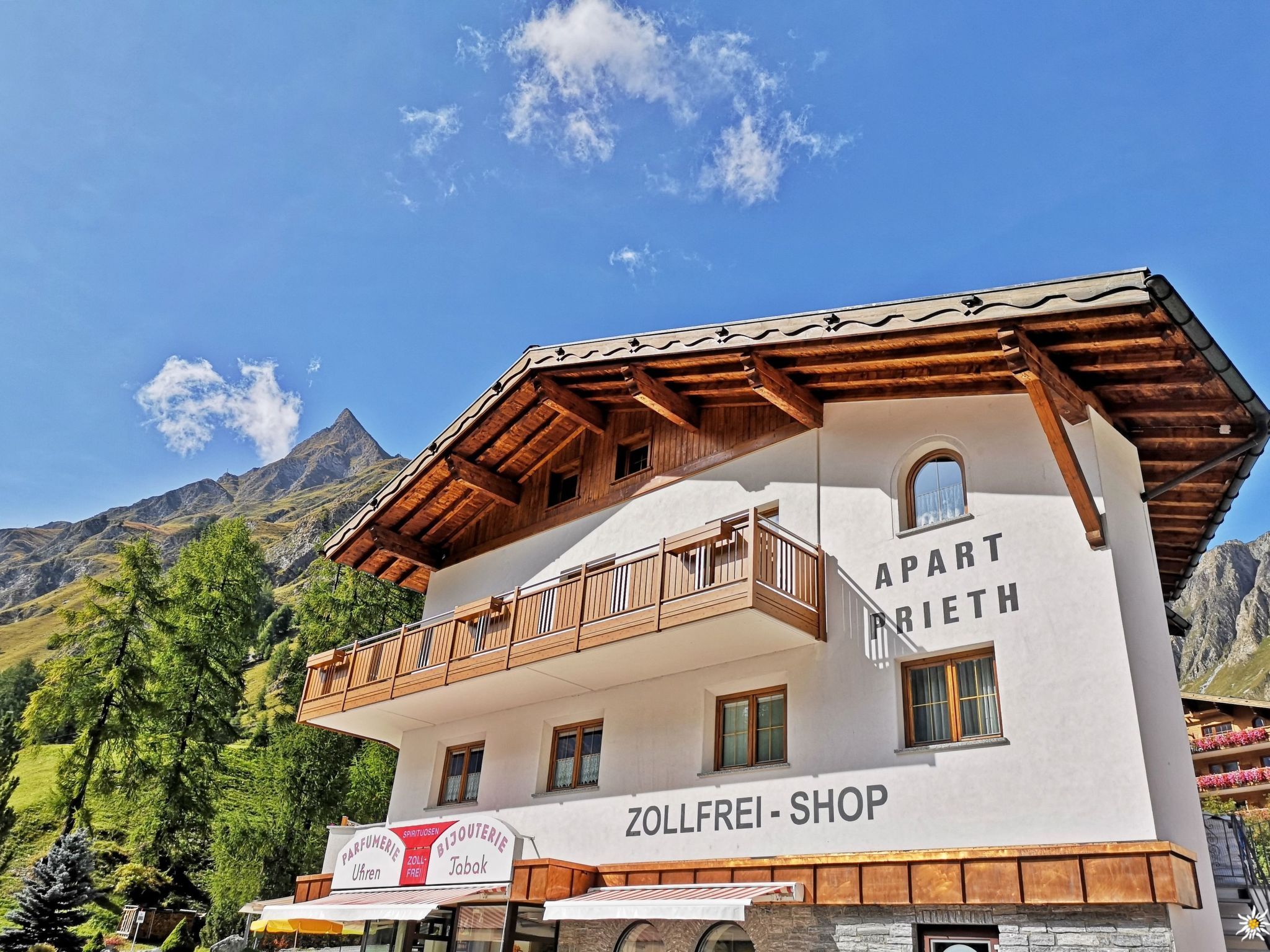 Ein zweistöckiges Gebäude mit einem Balkon, beschriftet mit 'APART BRIETH' und 'ZOLLFREI-SHOP' unten.