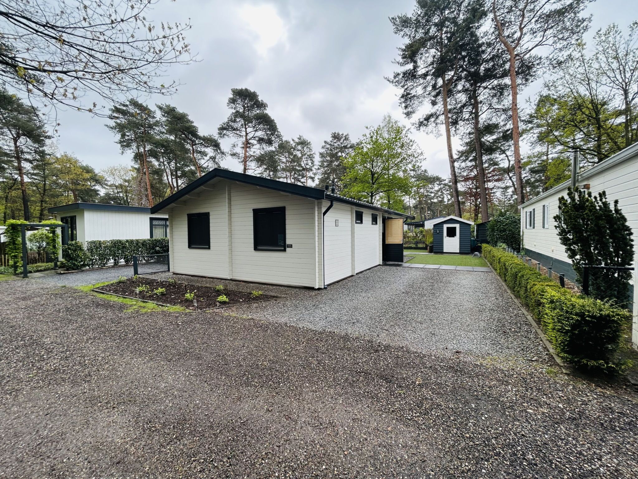 Een laag, enkelvoudig gebouw met een grindpad en een kleine tuin.