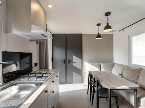 Una cocina moderna con estufa a gas, lavamanos y un comedor con mesa y sillas.