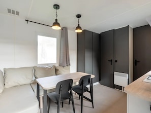Una cocina moderna con una mesa de madera, sillas negras y lámparas colgantes.