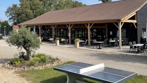 Un'area esterna con tavoli e sedie, un padiglione coperto e un tavolo da ping pong.