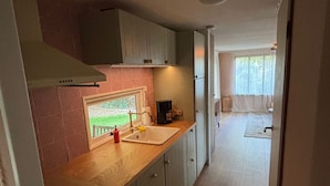 Eine schmale Küche mit Spüle, Schränken und einem Fenster.