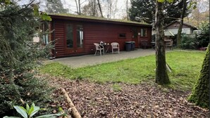 Ein rustikales Blockhaus mit Terrasse, Tisch und Stühlen.