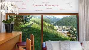 Una stanza con vista su un villaggio, un tavolo di legno, un divano rosso e un'orchidea in vaso.