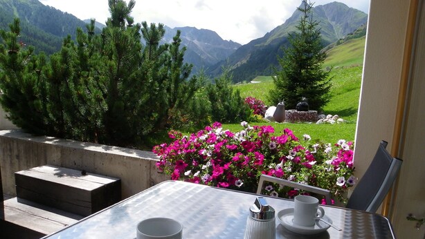 Un tavolo con una tazza, un piattino e un piccolo contenitore per il sale, con montagne sullo sfondo.