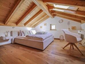 A cozy attic bedroom with a sloped ceiling, a bed, a chair, and a small table. - APARTMENT BERGWALDZAUBER – Haus zur Post, (Samnaun-Compatsch) by Interhome (Samnaun)