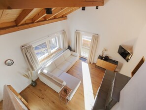 A spacious loft with a high ceiling, a sofa, a small table, and a television. - APARTMENT BERGWALDZAUBER – Haus zur Post, (Samnaun-Compatsch) by Interhome (Samnaun)