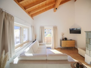A living room with a sofa, a television, and a wooden ceiling. - APARTMENT BERGWALDZAUBER – Haus zur Post, (Samnaun-Compatsch) by Interhome (Samnaun)