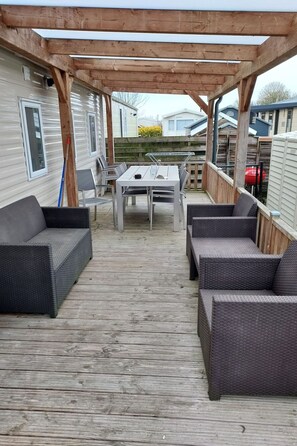 A covered outdoor deck with a table and chairs, surrounded by wicker sofas. - RBR 1152 - Beach Resort Kamperland by Interhome (Kamperland)
