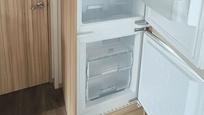 Un refrigerador obert amb diverses prestatgeries i un compartiment congelador.