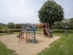 A playground with climbing structures, a slide, and a picnic table. - Camping Gritt - Lodge by Interhome (Ingeldorf)