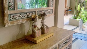 Une console en bois ornée de sculptures complexes, un miroir avec un cadre richement décoré et deux petites statues.