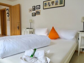 Ein Hotelzimmer mit Bett, Kissen, einem Nachttisch, einer Lampe und gerahmten Bildern an der Wand.