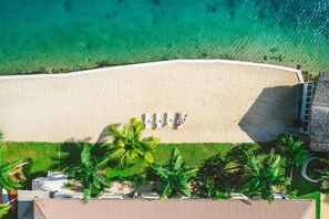 An aerial view of a beach with a row of sun loungers and palm trees. - Tropicana Lagoon Resort (Port Vila)