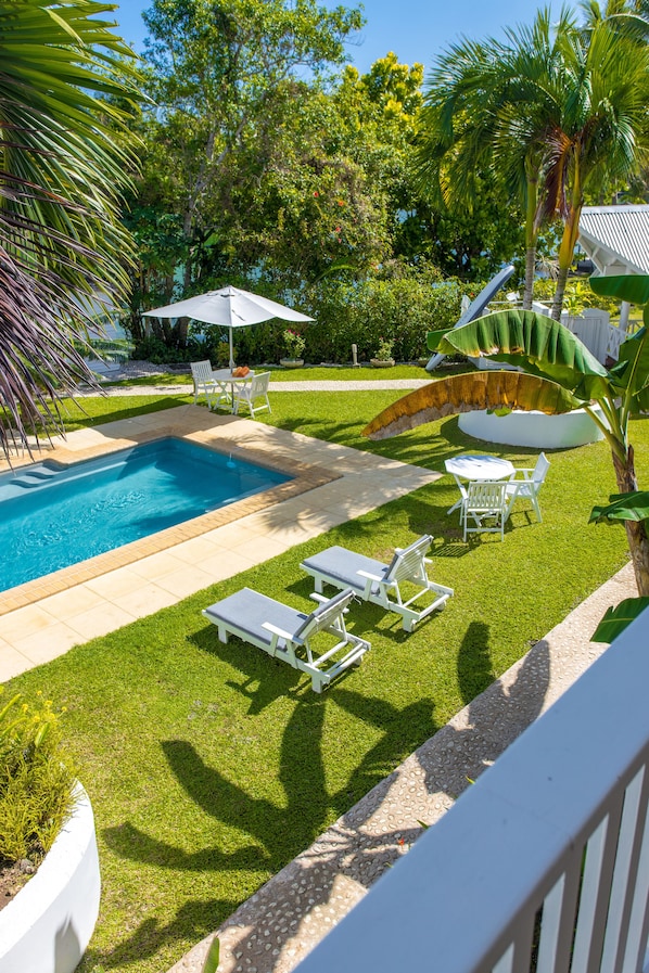 A swimming pool with lounge chairs and umbrellas, surrounded by well-maintained grass and palm trees. - Tropicana Lagoon Resort (Port Vila)