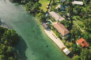 An aerial view of a coastal property with a long pier, several buildings, and lush greenery. - Tropicana Lagoon Resort (Port Vila)