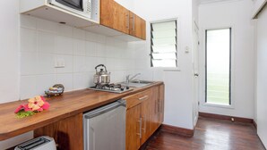 Una cocina con armarios de madera, un refrigerador de acero inoxidable, un microondas y una estufa a gas.