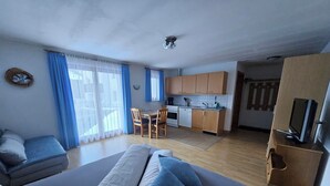 Ein kompakter Wohnbereich mit Küchenzeile, Essecke und einer Sitzecke mit Sofa und Sesseln.