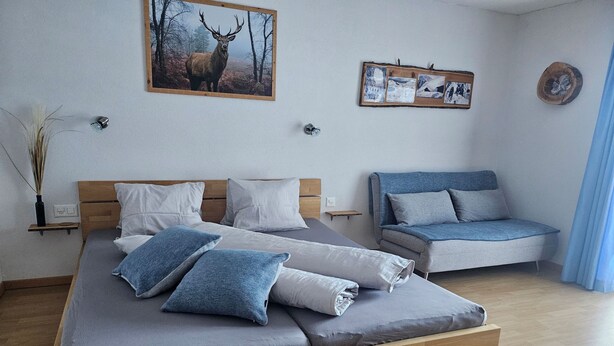 Ein modernes Schlafzimmer mit einem großen Bett, einer Couch und einem Wandbild von einem Reh.
