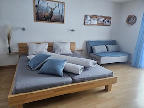 Ein Schlafzimmer mit einem Bett, einer Couch und einem an der Wand hängenden Bild.