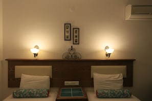 Ein Hotelzimmer mit zwei Betten, jeweils mit Kopfteil, Nachttischlampen und einem kleinen Tisch dazwischen.