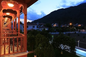 Eine Holztreppe führt zu einem Balkon mit Blick auf ein Wohngebiet und einen Berg im Hintergrund.