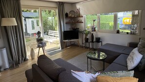 Ein modernes Wohnzimmer mit einer großen Couch, einem Fernseher und einem kleinen Tisch.
