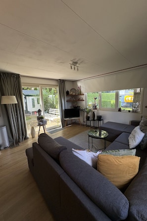 Ein modernes Wohnzimmer mit einer großen Couch, einem Fernseher und einem kleinen Tisch.